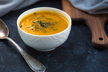 Pumpkin cream soup. Fresh soup with herbs on a background, Autumn concept. Tasty healthy food.
