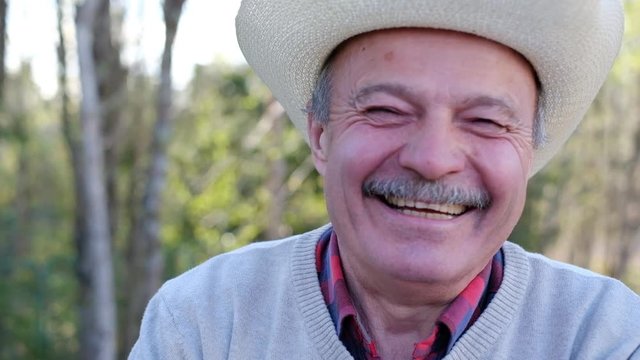 Elderly man in hat laughing and smiling outdoors in nature