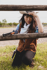 Portrait of a beautiful Chinese female cowgirl shooting with a weapon