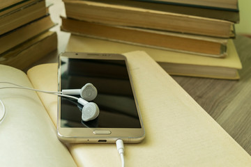 On the page of an open book is a smartphone and headphones