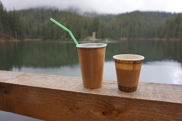 Two paper cups are on the parapet. In the background is a lake with turquoise water.