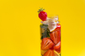 Infused or detox water with strawberry and lemon  in the bottle  on the yellow background.Copy space.Closeup.