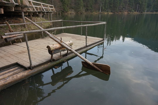 Wooden homemade oar, which row the water in the lake.