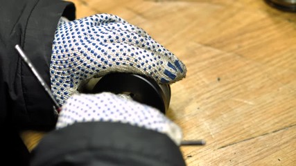 A factory worker assembles a part by hand. A worker assembles a detail on a desk in a workshop.