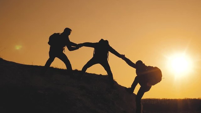 teamwork lifestyle help business travel silhouette concept. group of tourists lends a helping hand climb the cliffs mountains. people climbers climb to the top overcoming hardships the path to victory