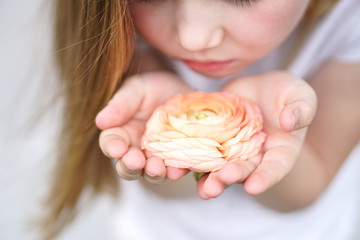 Girl carefully holding a beautiful delicate flower . Childhood protection