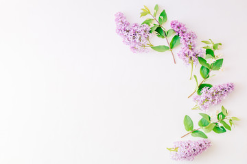 Flat lay composition with branches of lilac and branches with green leaves on a white background