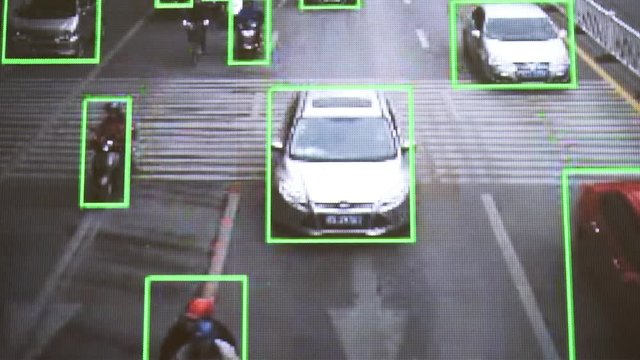 CCTV camera. Real-time tracking of vehicles and people on the street. Authentic pixelated image from a real monitor.