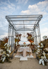 Romantic dinner setup placed on the beach with flowers and chandelier  prepared for marriage proposal