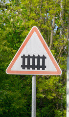 Blue and red road sign on a sunny day among green leaves