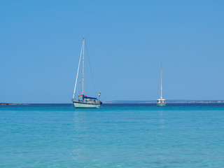 Fototapeta premium Colonia Sant Jordi, Ses Salines, Spain. Amazing view of the boats in turquoise sea close to the charming beach of Es Trenc. It has earned the reputation of Caribbean beach of Mallorca