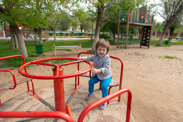 boy on the playground rides on a swing