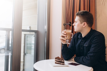 Handsome brutal business man student sitting in cafe drinking coffee in the morning. Breakfast,  business, coffee concept
