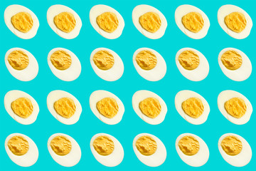 Rows of many halves of boiled eggs on a blue background
