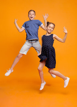 Happy Little Girl And Boy Jumping For Joy Together