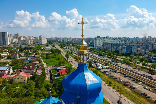 golden cross on the blue dome of the temple on the background of the city