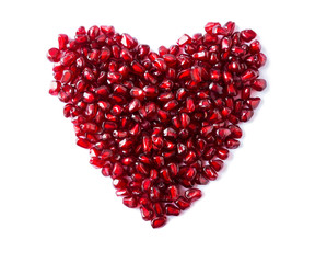Heart shape pomegranate seeds on white background. Background made of red pomegranate seeds. The...