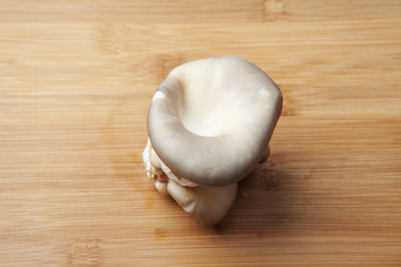 Fresh oyster mushroom clusters laid out on a natural bamboo cutting board.