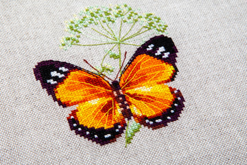 Cross-stitch butterfly with pink wings.
