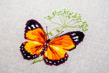 Fototapeta na wymiar Cross-stitch butterfly with pink wings.