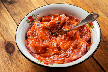 raw meat marinated in sauce for barbecue in a metal Cup on a wooden table