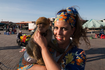 Beautiful brunette woman portrait with a headscarf and a monkey in her arms