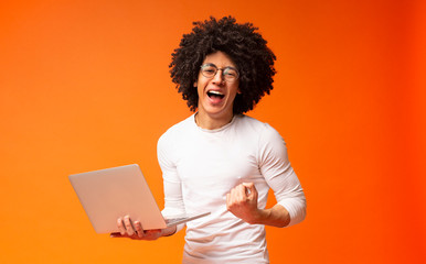 African-american guy enjoying achievement with laptop and screaming