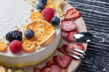 Dietary delicate fruity berry nut cake without baking. Wooden stand on a black table.