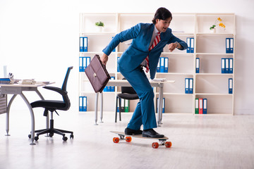 Young handsome businessman with longboard in the office 
