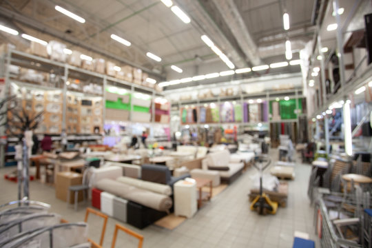 Blurred concept of DIY shopping center. Shelving with household products, kitchenware and furniture. Commercial LED lighting. Merchandising in retail.