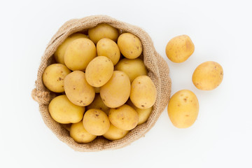 Sack of fresh raw potatoes on wooden background, top view