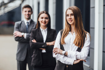 Business woman sitting i with crossed arms , looking at camera, smiling, two business  people  in background. Your future at your hands!