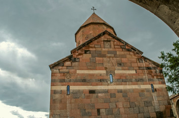 The backside of the medieval Church of the Holy Virgin with carved crosses on the wall and the dome on the background of rain clouds in the sky