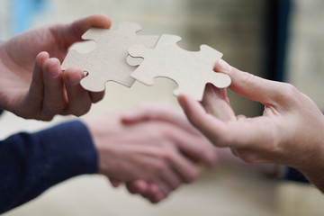 Two men handshake trying to connect couple puzzle piece.Symbol of association and connection....