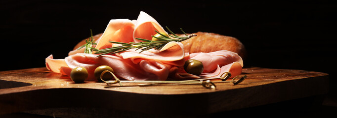 Sliced ham on wooden background. Fresh prosciutto cotto. Pork ham sliced with herbs