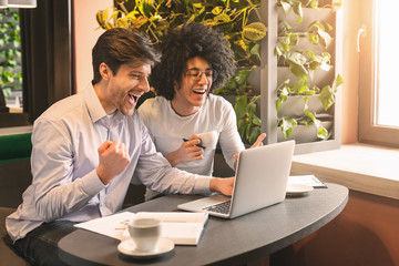 Happy millennial men looking at laptop enjoying great news