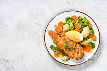 Grilled salmon fish steak with vegetables on white.