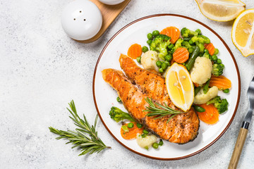 Grilled salmon fish steak with vegetables on white.