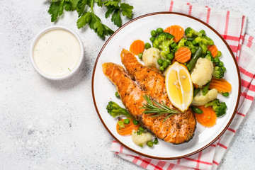 Grilled salmon fish steak with vegetables on white.