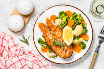 Grilled salmon fish steak with vegetables on white.