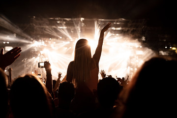 Rear view of carefree woman enjoying on music concert at night.