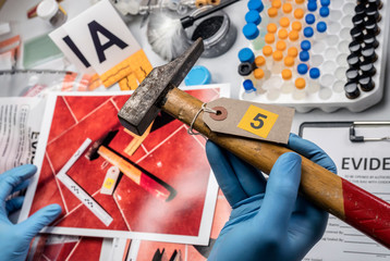 Police scientist analyses hammer from crime scene at laboratory criminologist