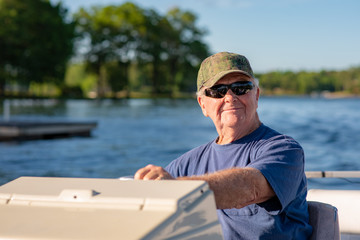 A senior man enjoys driving a boat on a beautiful lake on a sunny day.