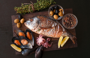 Grilled Dorado with tomatoes, onions and thyme on a wooden Board. The view from the top.
