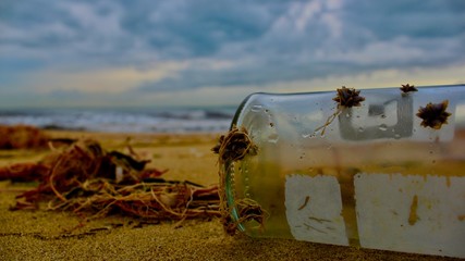 Old bottle with shells on the sandy beach with a great heaven and horizon