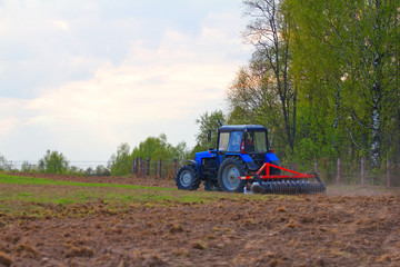 Obraz premium Blue tractor in the back with a plow in the field