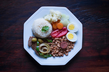 Fototapeta na wymiar Brazilian food dish - Beans, rice, meat, eggs, salad