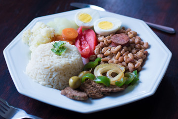 Brazilian food dish - Beans, rice, meat, eggs, salad