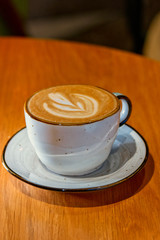 Ceramic cup of cappuccino served on wooden table shot with copyspace