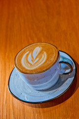 Ceramic mug of cappuccino served on wooden table shot with copyspace